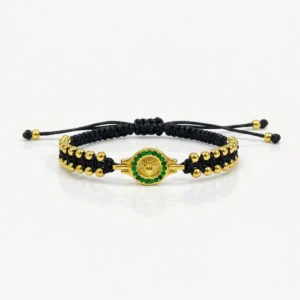 Pulsera Rolex diamantada en oro laminado con tejido negro ajustable, detalles dorados y dije central circular con incrustaciones verdes.