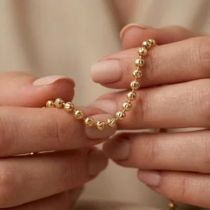 Cadena de balines diamantados en tono oro sostenida por manos femeninas, fotografía macro de joyería fina de Luxor SM Joyería Santa Marta.
