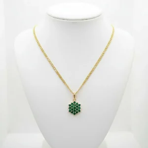 Cadena dorada con dije floral verde exhibida en busto blanco en Luxor SM Joyería Santa Marta.