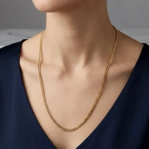 Cadena cubana de 60 cm en tono oro puesta en el cuello de una mujer elegante, con estilo de joyería premium.