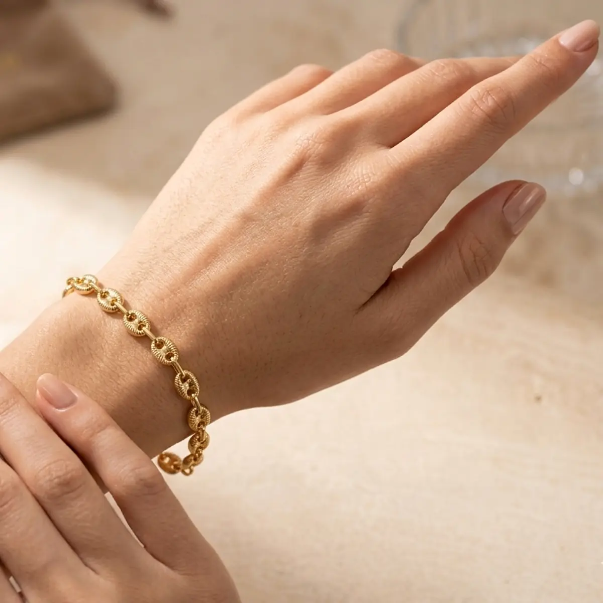 Pulsera Gucci en tono oro puesta en mano femenina elegante, con eslabones ovalados y relieves en fotografía de joyería premium.