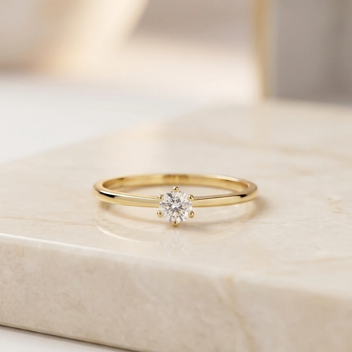 Anillo solitario dorado para compromiso sobre base beige de joyería premium, disponible en Luxor SM Joyería Santa Marta.