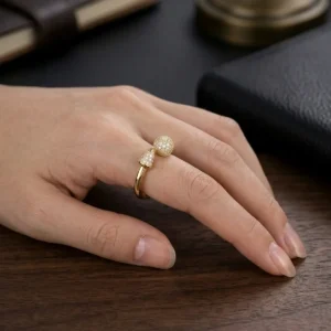 Anillo de compromiso dorado con microincrustaciones brillantes sobre mano femenina elegante, joya de Luxor SM Joyería en Santa Marta.