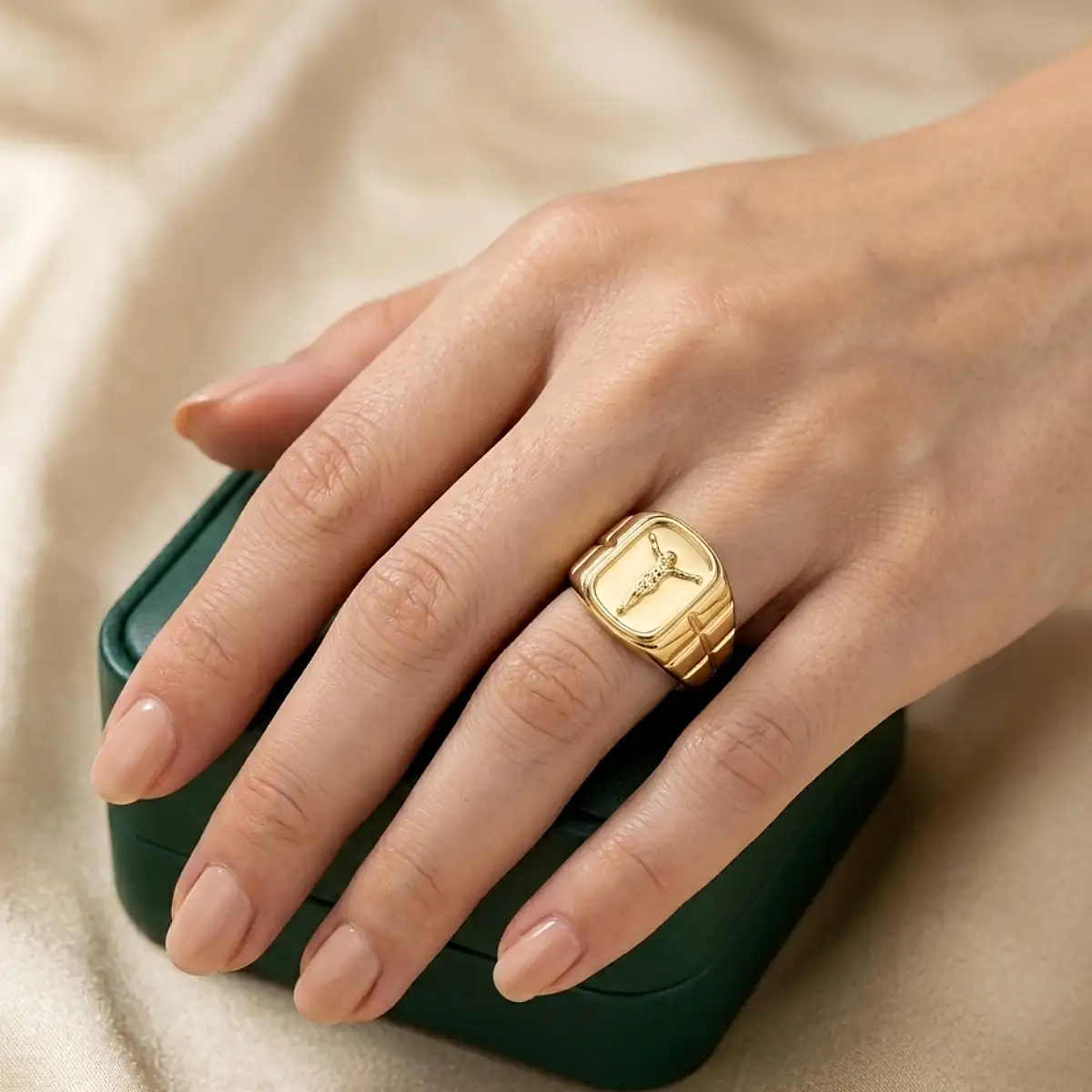 Anillo de Jesucristo dorado para mujer sobre mano femenina elegante, joya religiosa de Luxor SM Joyería en Santa Marta.