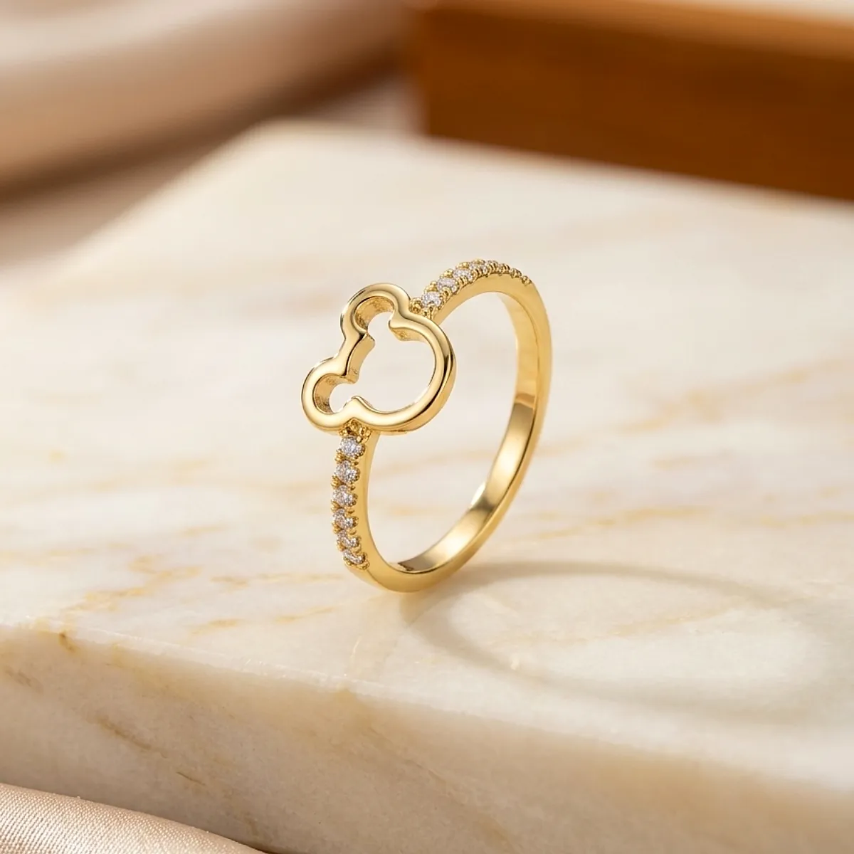 Anillo dorado con diseño tipo trébol y microincrustaciones sobre base de mármol claro, joya femenina de Luxor SM Joyería en Santa Marta.