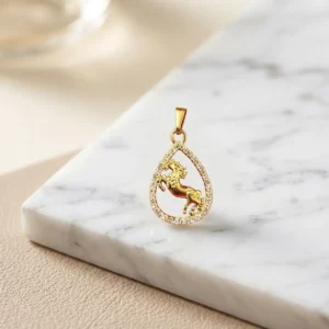 Dije gota dorado con caballo en relieve y borde brillante sobre base de mármol claro, joya elegante de Luxor SM Joyería en Santa Marta.