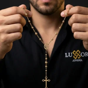 Rosario dorado en oro laminado sostenido por hombre, joya religiosa elegante de Luxor SM Joyería en Santa Marta.